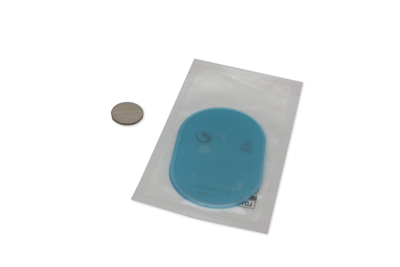Blauw object in verpakking naast een munt op een witte achtergrond.